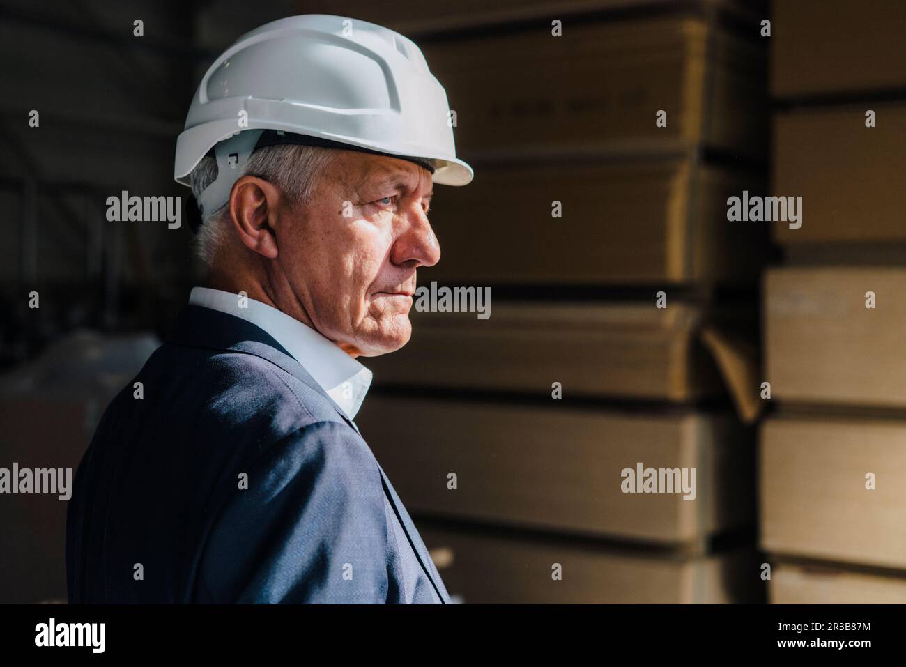 Homme d'affaires senior contemplatif portant un casque dans une usine de menuiserie Banque D'Images