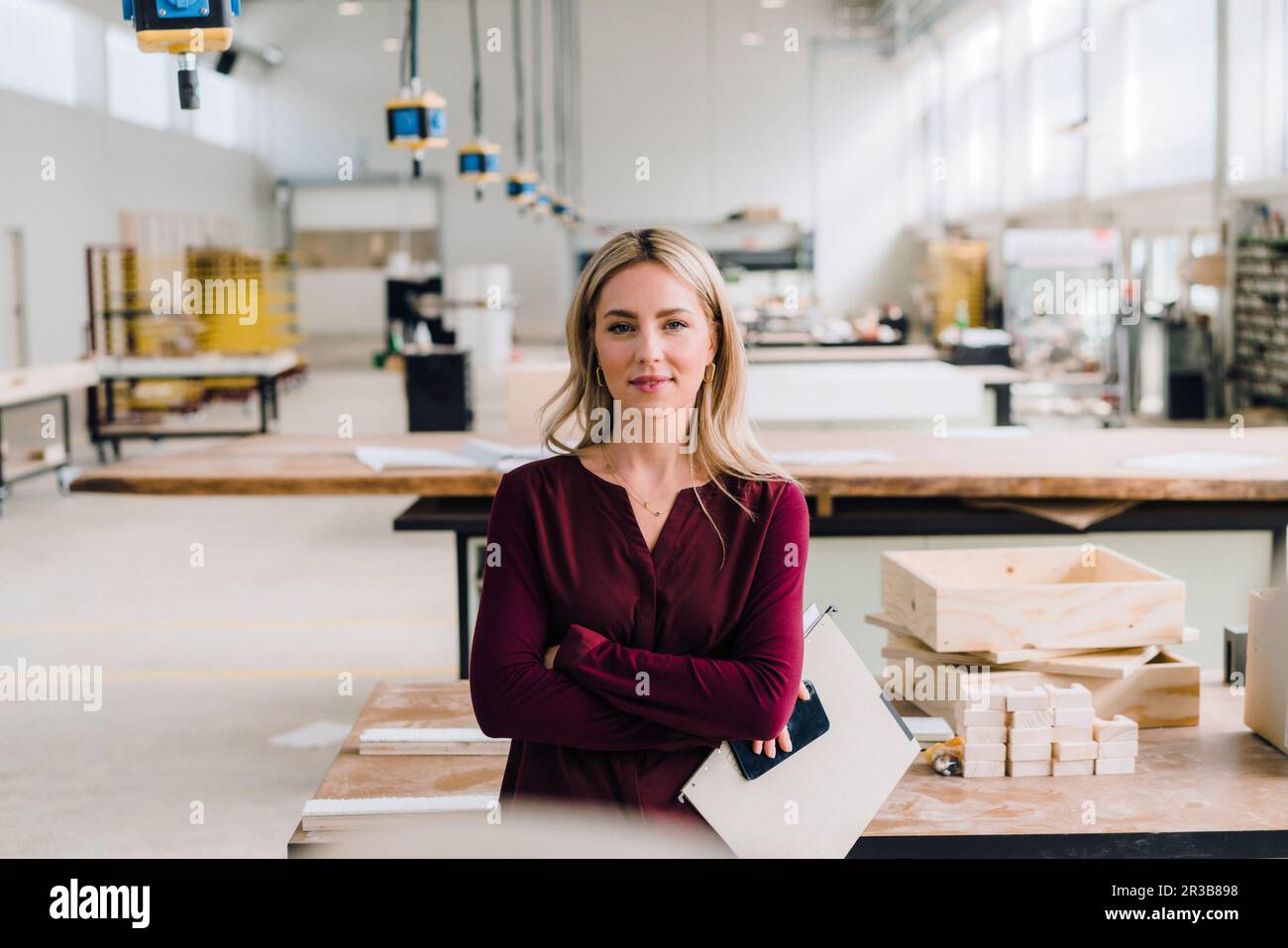 Femme d'affaires confiante aux bras croisés dans l'usine de menuiserie Banque D'Images