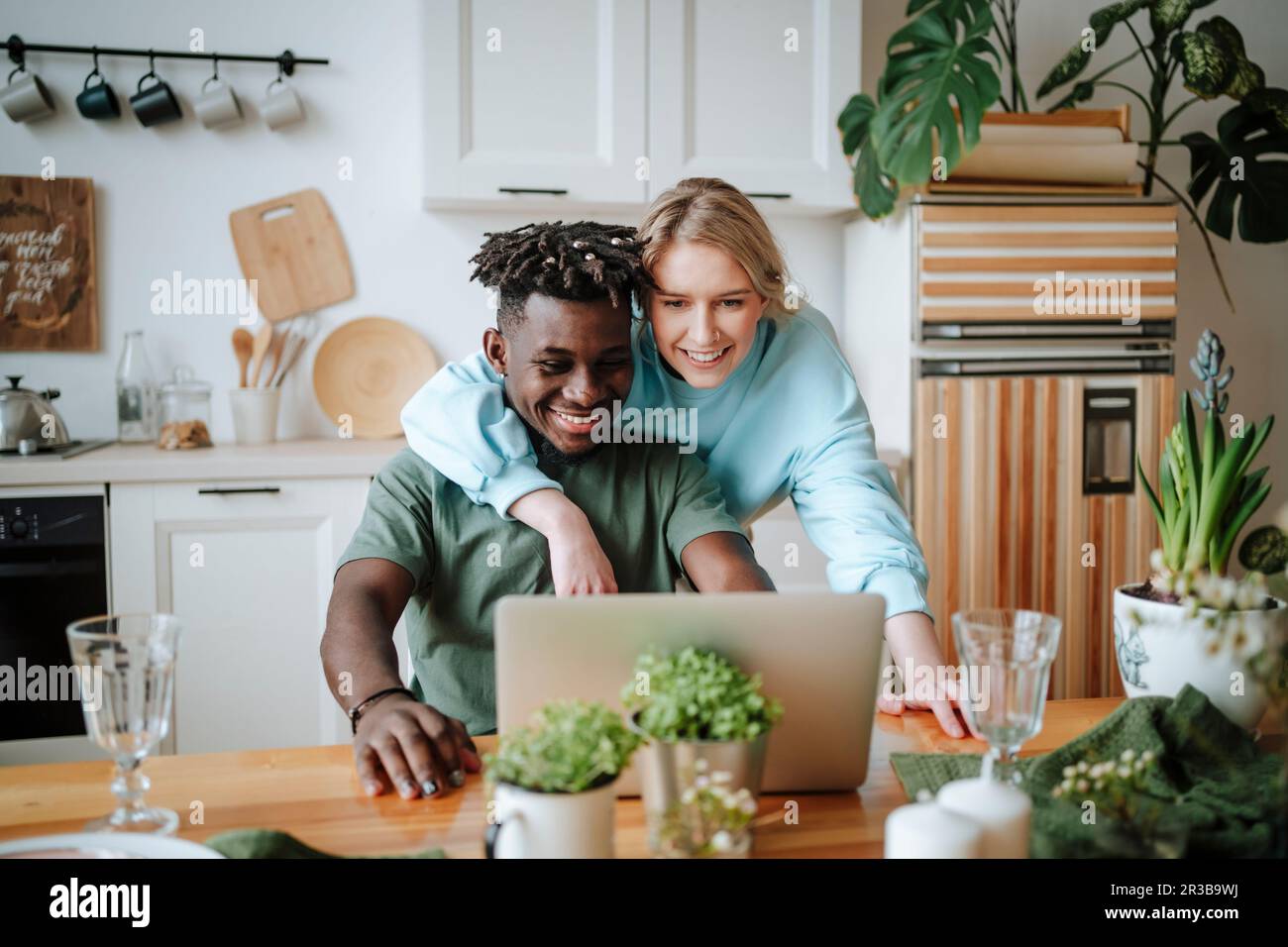 Femme avec le bras autour de l'homme utilisant un ordinateur portable à la maison Banque D'Images