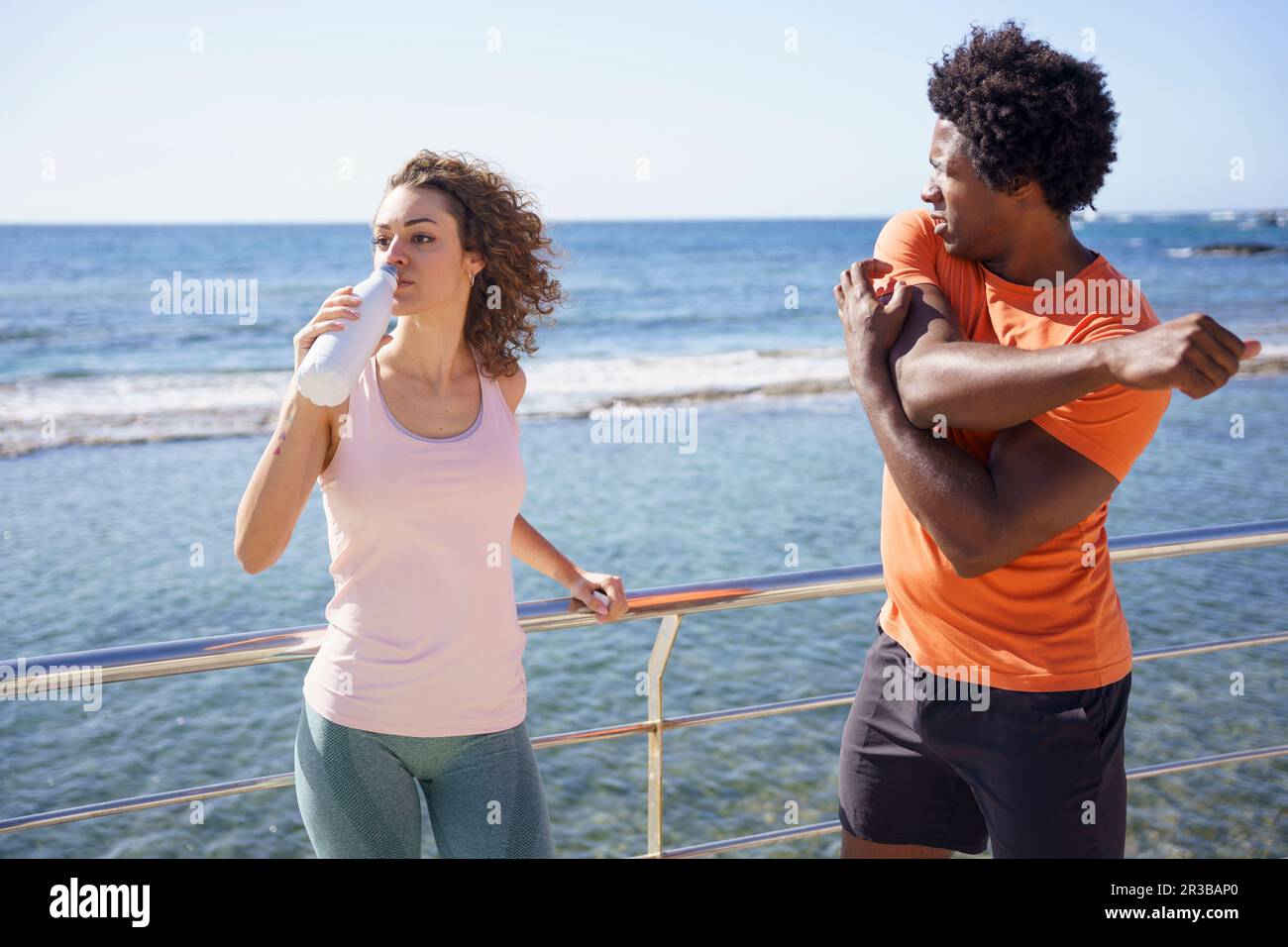Homme s'exerçant avec une petite amie de l'eau potable par la rampe dans la zone côtière Banque D'Images