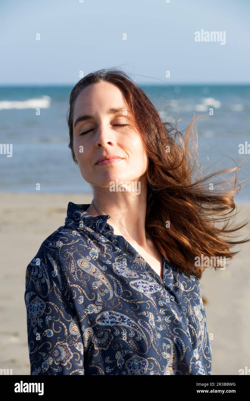 Femme mature avec les yeux fermés à la plage Banque D'Images
