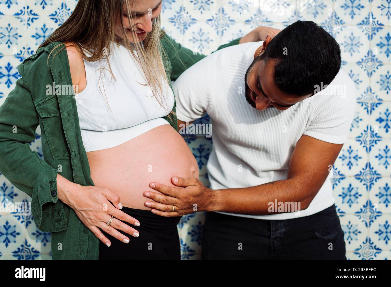 Homme touchant le ventre de la femme enceinte devant le mur de tuiles Banque D'Images