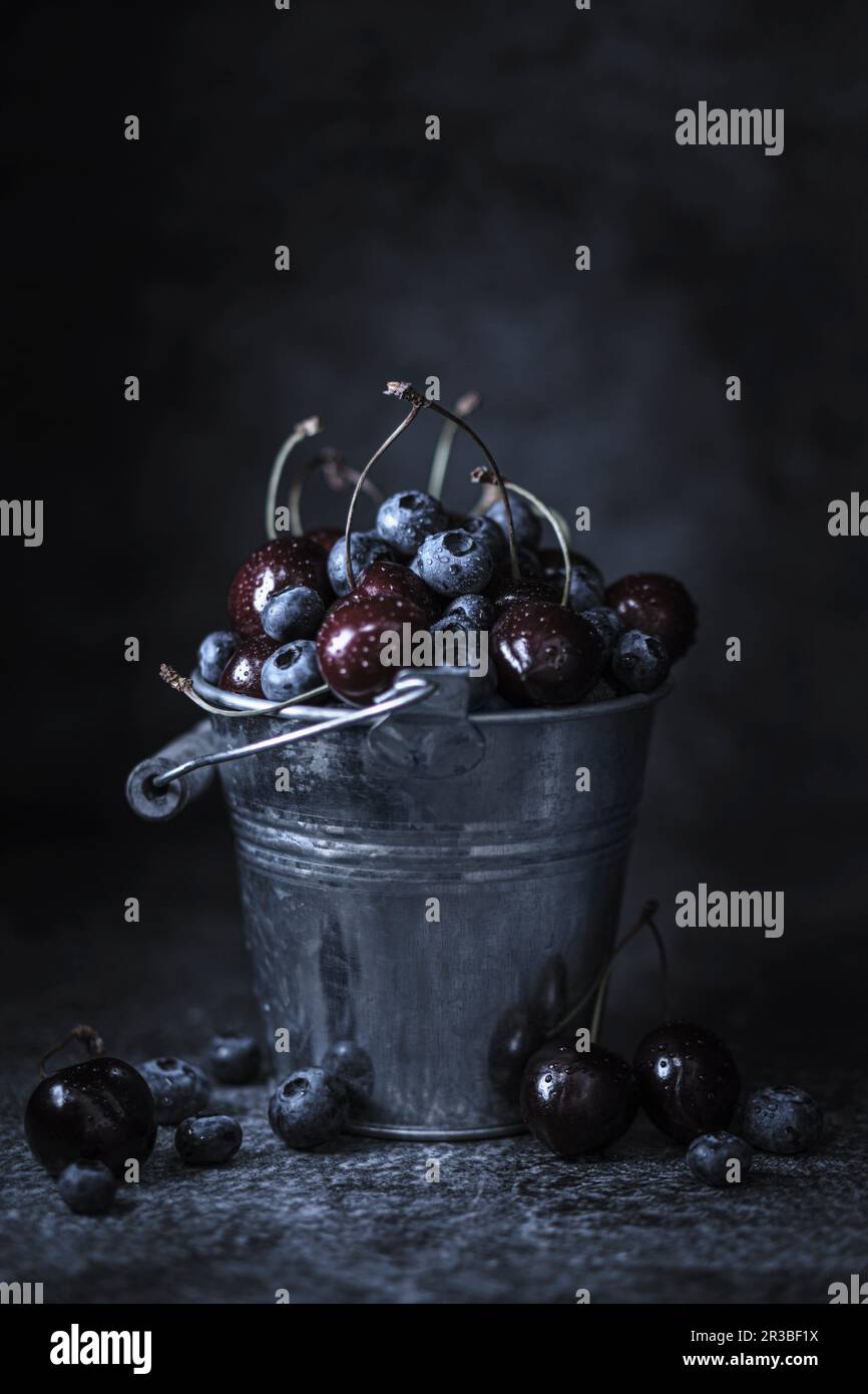 Bleuets et cerises dans un seau de zinc Banque D'Images