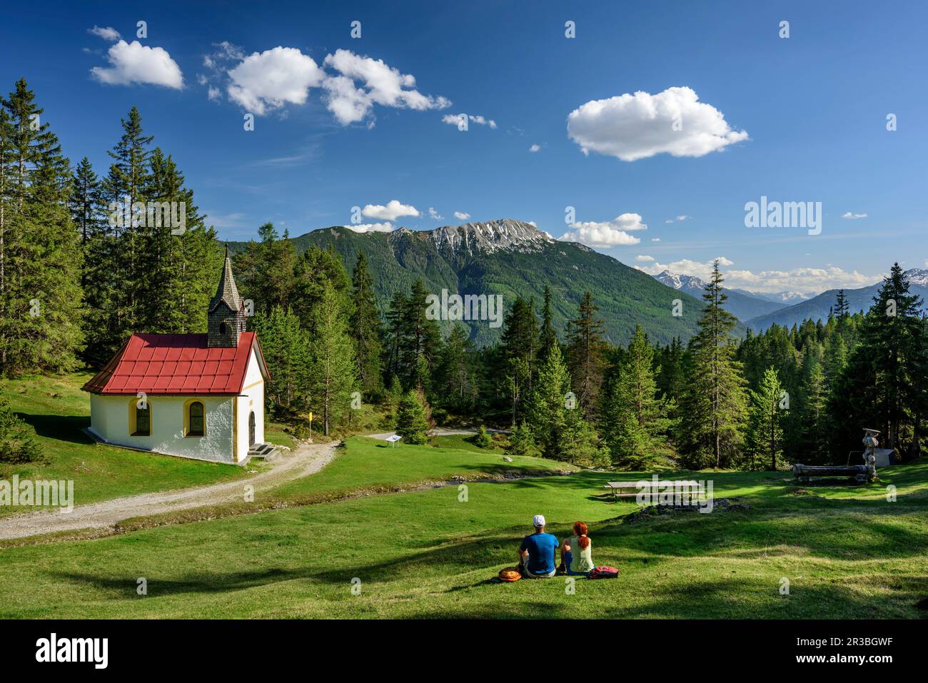 Autriche, Tyrol, couple de randonnée se reposant en face de la chapelle alpine Banque D'Images