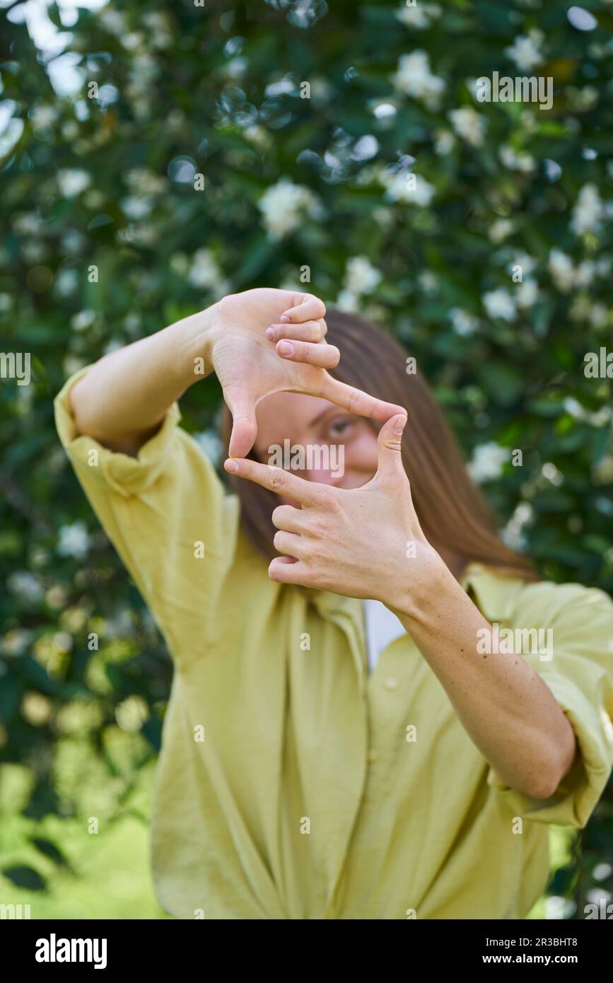 Femme faisant le cadre de doigt dans le jardin Banque D'Images