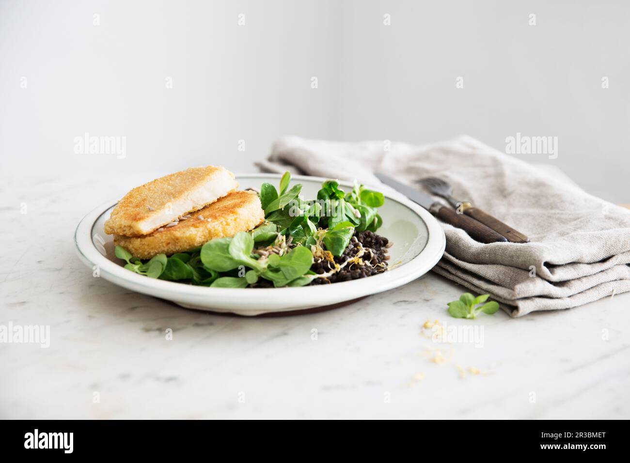 Escalopes panés de céleri-rave avec de la laitue d'agneau et des lentilles de béluga Banque D'Images