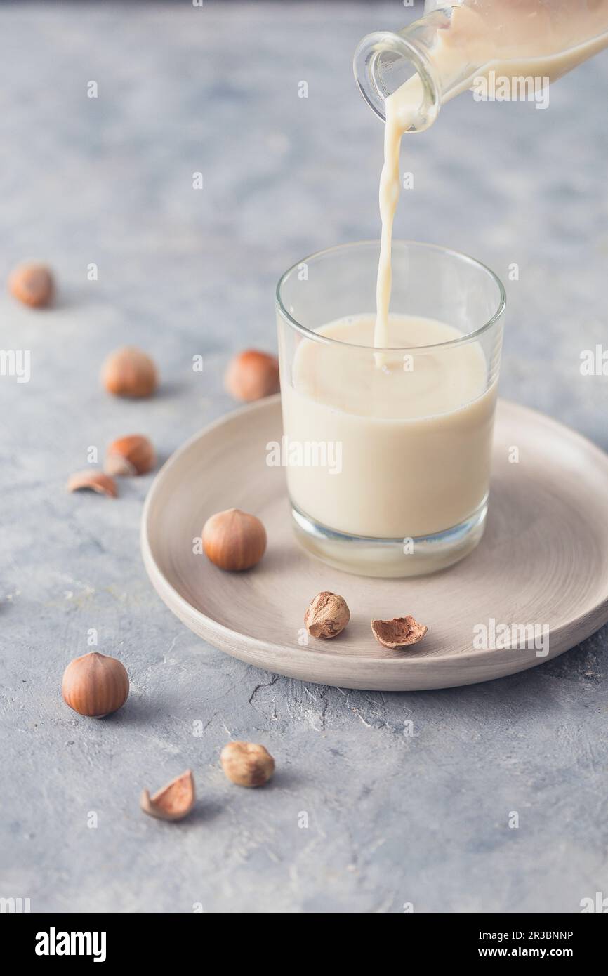 Verser le lait de noisette dans un verre Banque D'Images