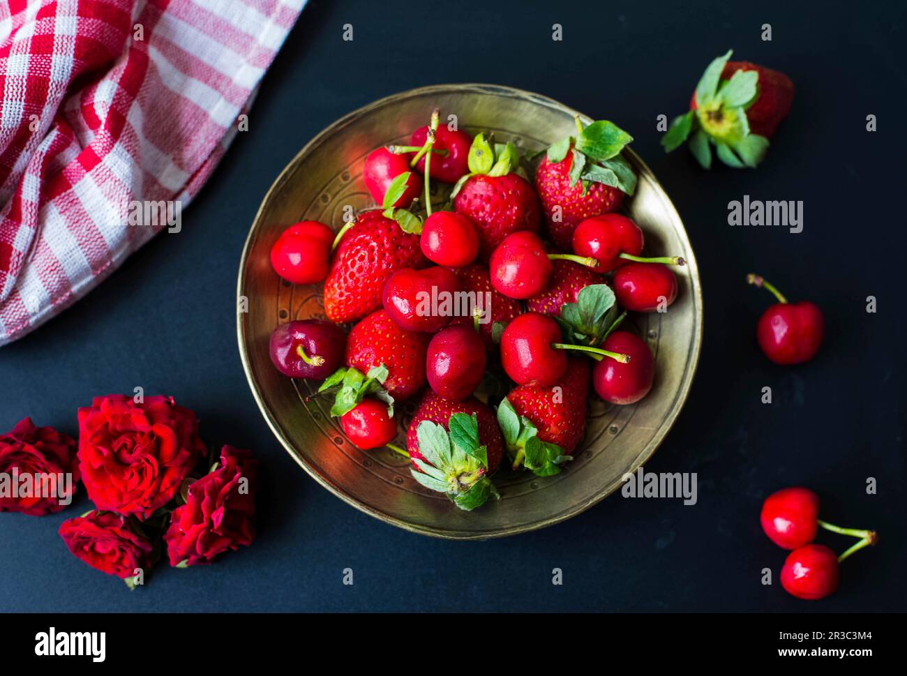 Cerises et fraises sur une assiette dorée Banque D'Images