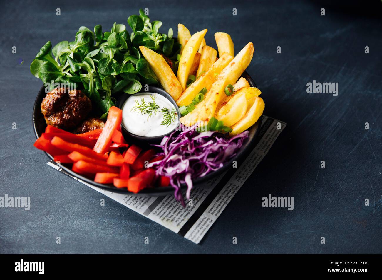 Bol végétarien coloré avec quartiers de pommes de terre et « petits boulettes » végétaliennes Banque D'Images