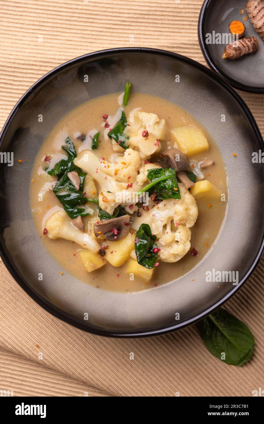 Curry de chou-fleur végétalien avec pommes de terre, champignons et épinards Banque D'Images