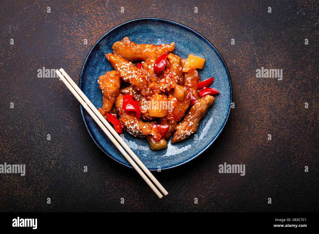 Wok traditionnel chinois poulet frit aigre-doux et aigre-profond avec légumes sautés sur l'assiette avec des graines de sésame Banque D'Images