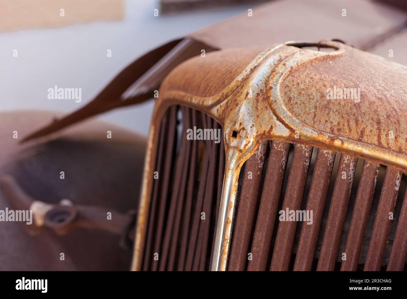 La grille avant d'une vieille voiture rouillée dans un parc à ferrailles Banque D'Images