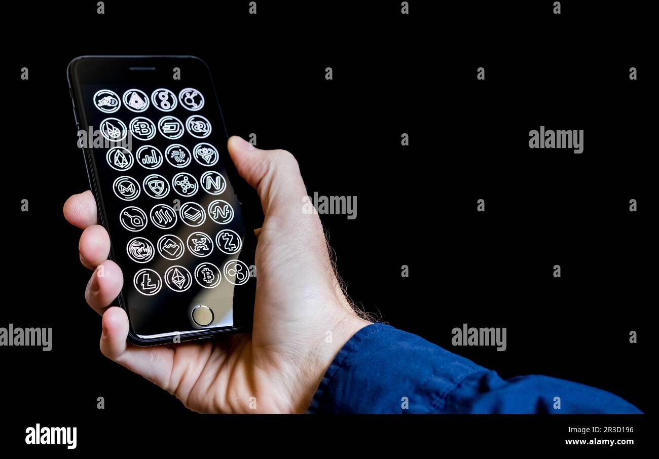 Main de caucasien Homme tenant un téléphone portable avec des icônes de crypto-monnaie sur l'écran Banque D'Images