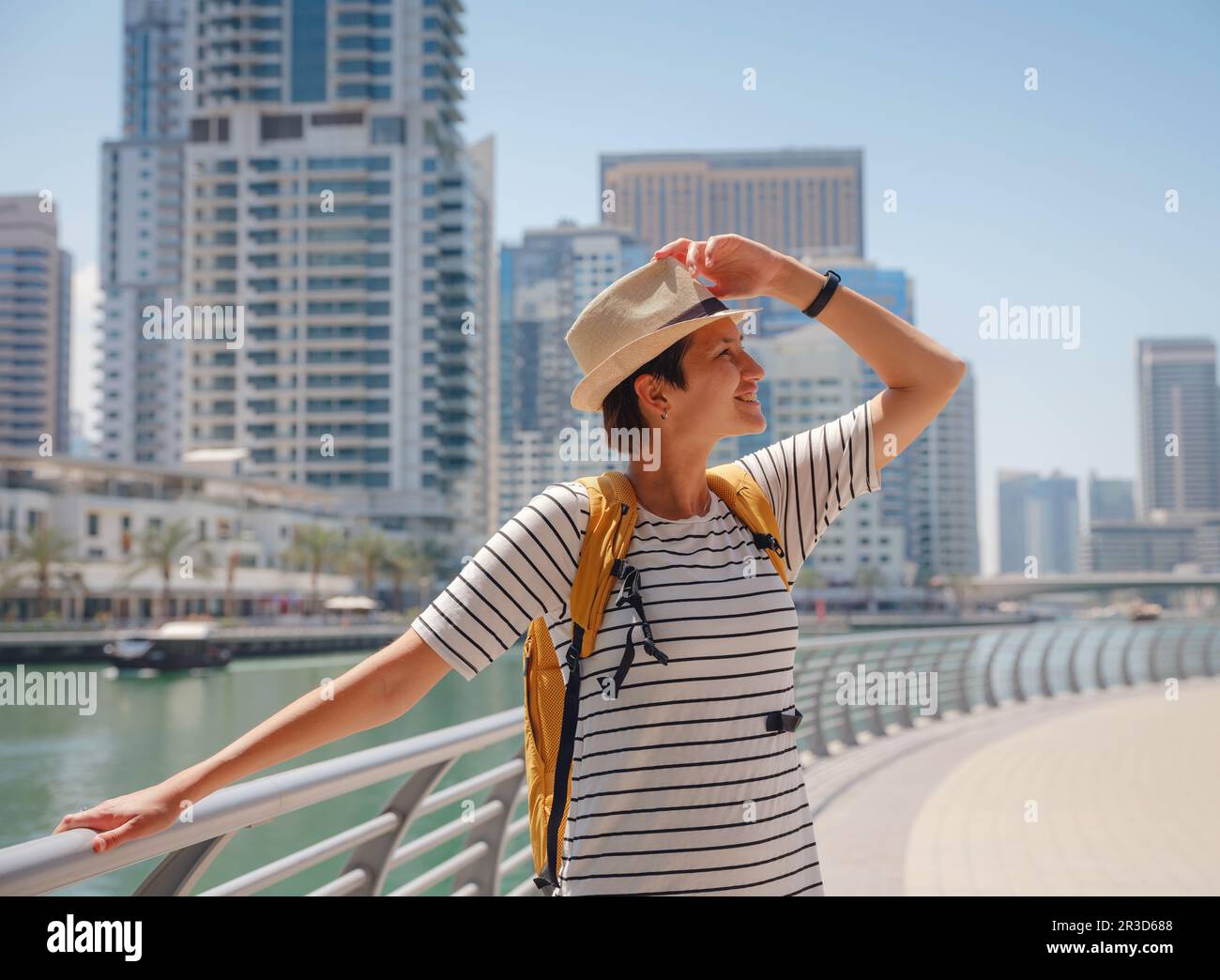 Attirante femme asiatique avec sac à dos jaune marchant sur la promenade dans le quartier Marina de Dubaï. Destinations de voyage et style de vie touristique aux Émirats Arabes Unis Banque D'Images