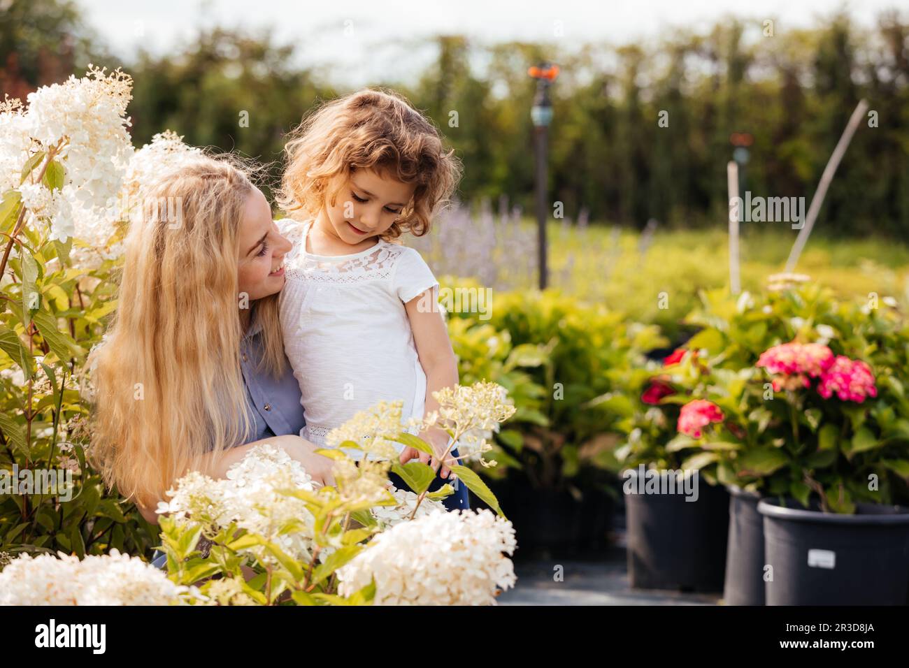 Maman et petite fille mignonne choisissent les plantes pour leur jardin Banque D'Images