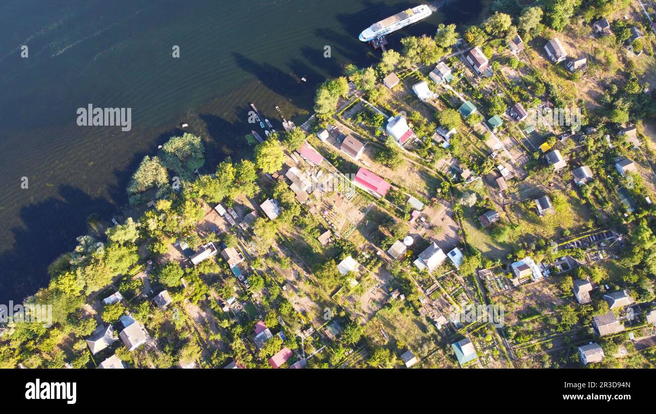 Un drone survole une rivière en agitant entourée d'un village local avec divers bâtiments et marais et marais Banque D'Images