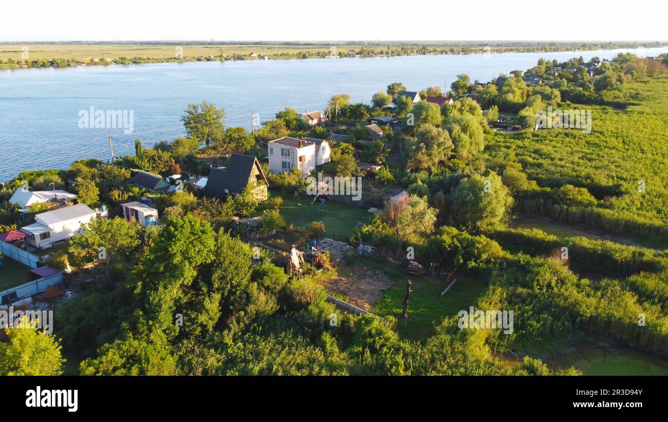 Un drone survole une rivière de couleur bleue entourée d'un village local avec divers bâtiments et un habitat dans les marais et les zones humides Banque D'Images