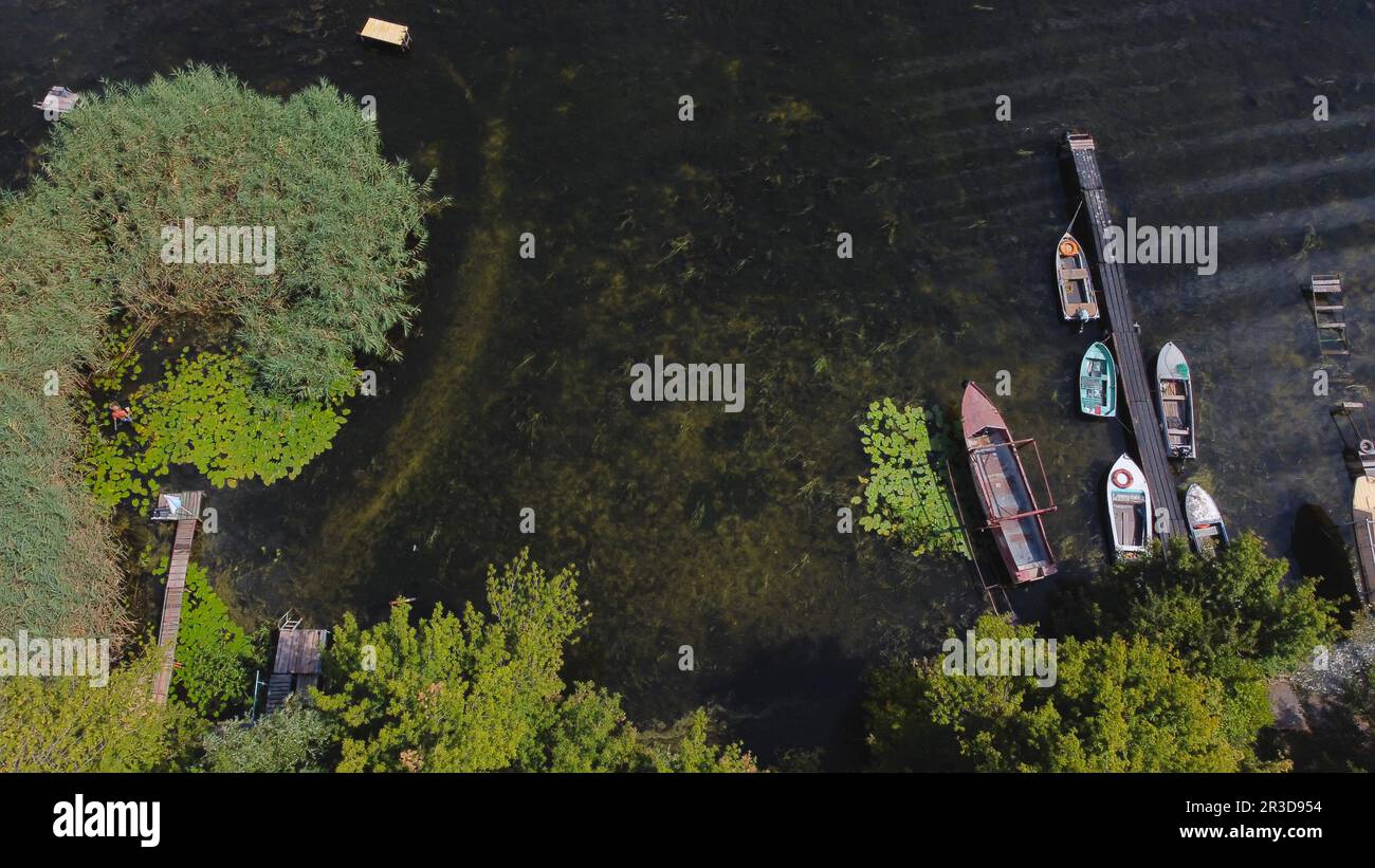 Un drone survole une rivière de couleur bleue entourée d'un village local avec divers bâtiments et un habitat dans les marais et les zones humides Banque D'Images