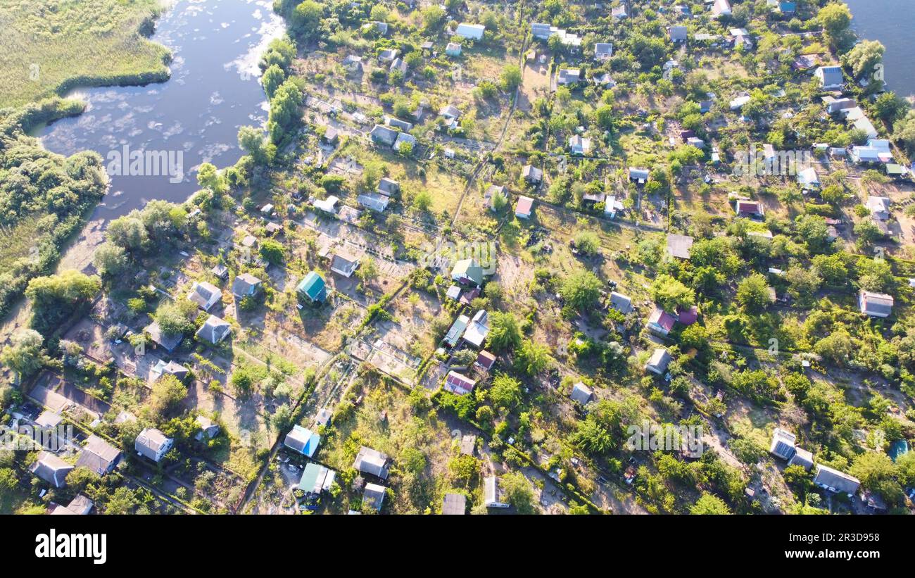 Un drone survole une rivière en agitant entourée d'un village local avec divers bâtiments et marais et marais Banque D'Images