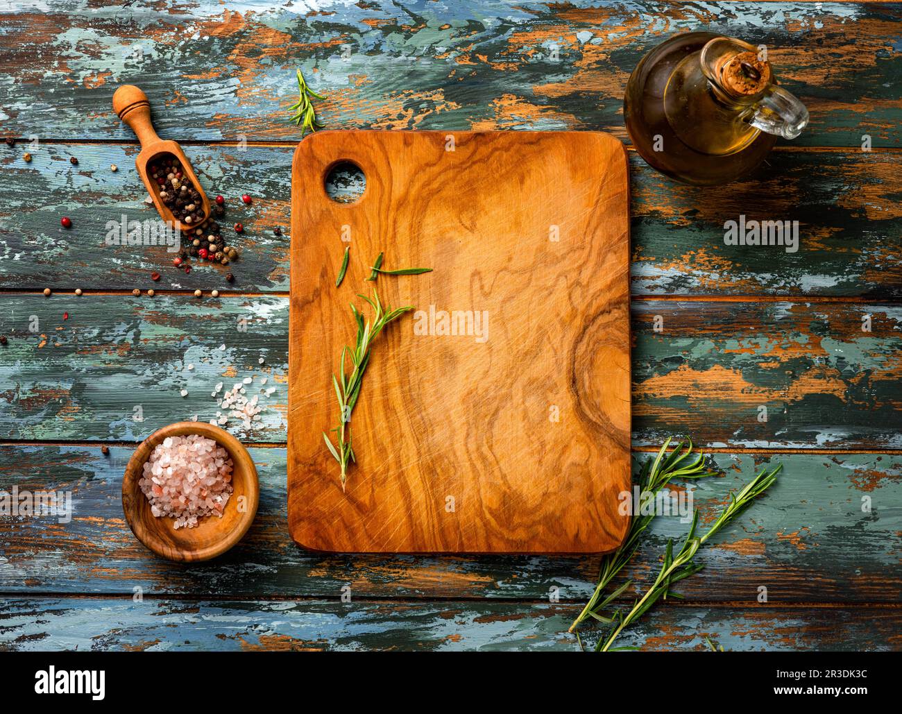 Plateau en bois avec épices, huile d'olive et sel rose sur table bleue Banque D'Images