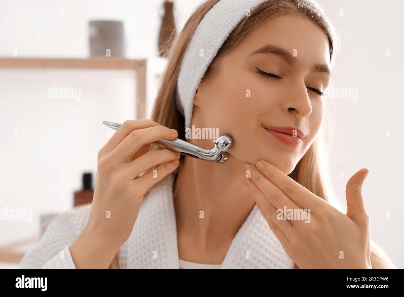 Jeune femme avec outil de massage du visage dans la salle de bains, gros  plan Photo Stock - Alamy