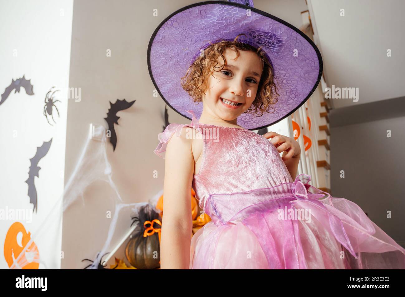 Adorable fille posant en robe rose et chapeau de sorcière Banque D'Images