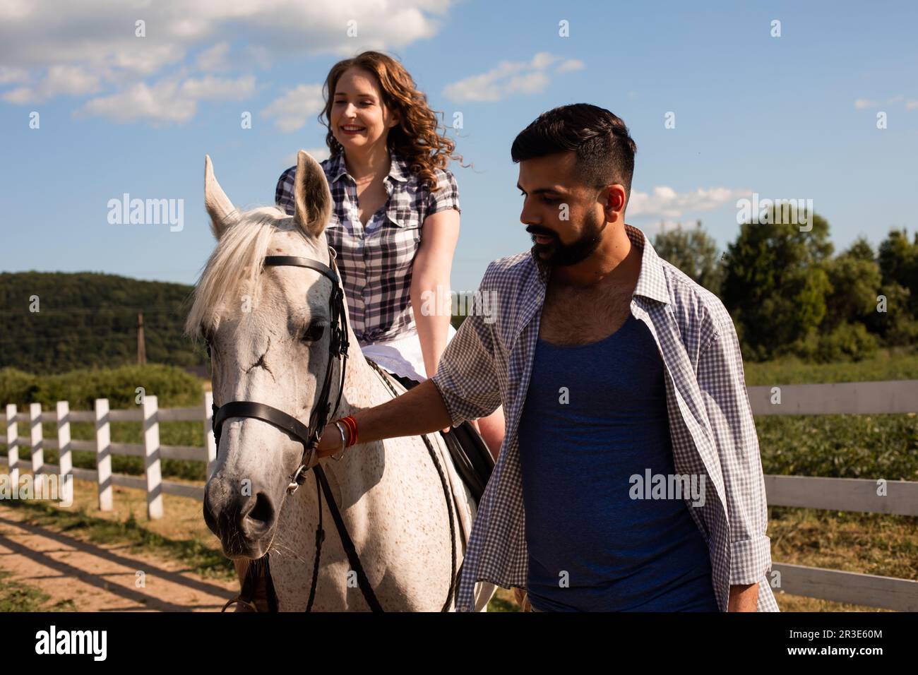 Le jeune homme aide une femme à monter à cheval Banque D'Images