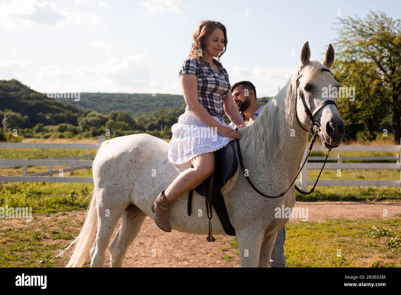 L'homme enseigne à une femme de monter à cheval Banque D'Images