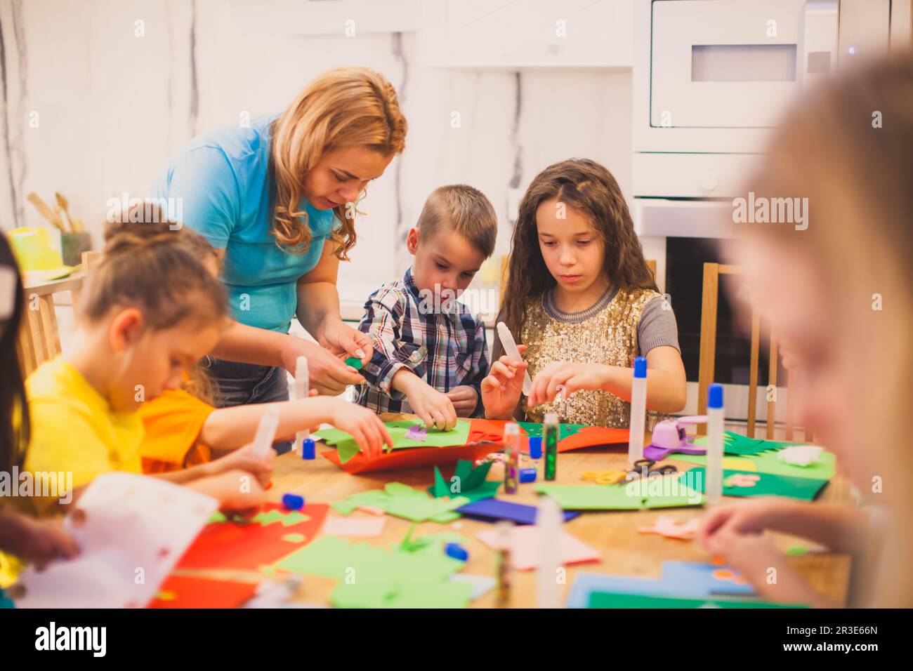 Les enfants d'âge préscolaire font une applique sous la supervision d'un éducateur Banque D'Images