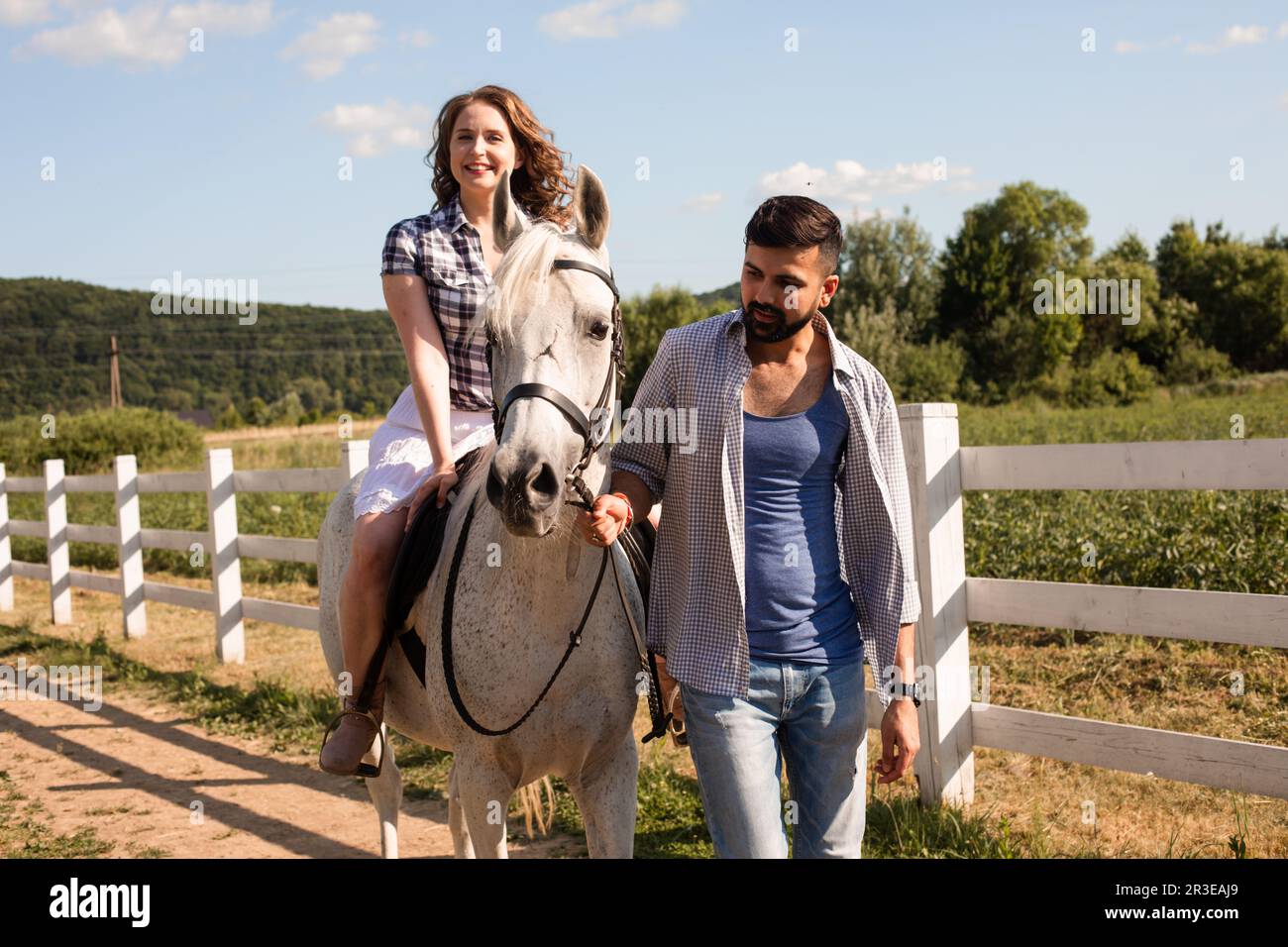 Le jeune homme aide une femme à monter à cheval Banque D'Images