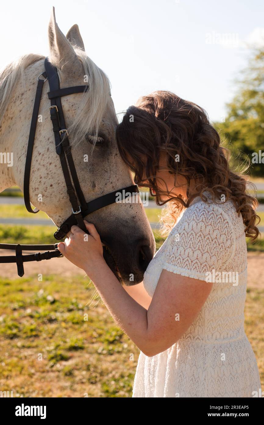 La femme avec les cheveux bouclés se caucus à son cheval Banque D'Images