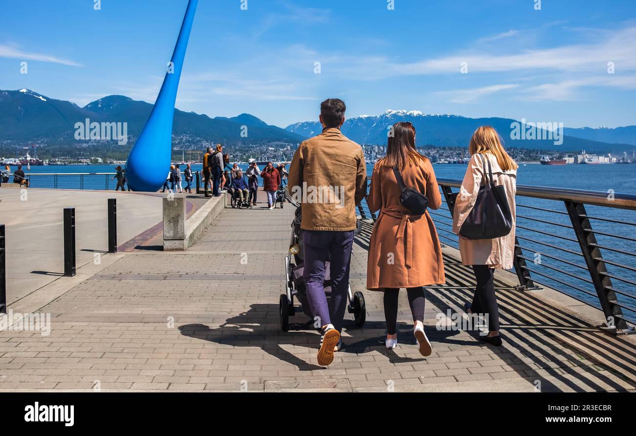 Une jeune famille pousse des poussettes pour bébés et marche sur le trottoir au parc urbain de Vancouver Canada. Jeune famille marchant dans le parc avec la poussette de bébé dans un c Banque D'Images