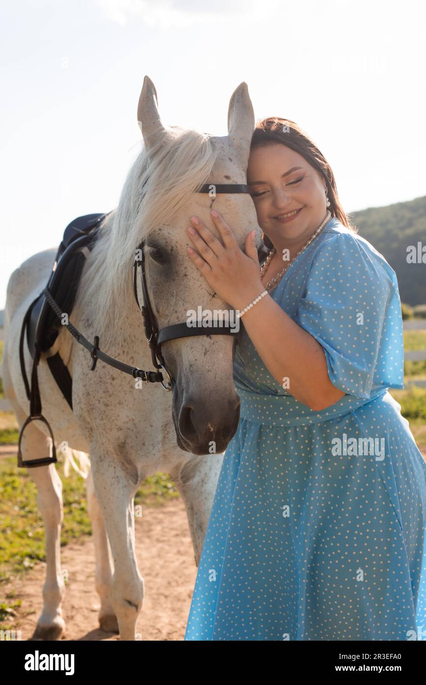 La femme avec les cheveux bouclés se caucus à son cheval Banque D'Images