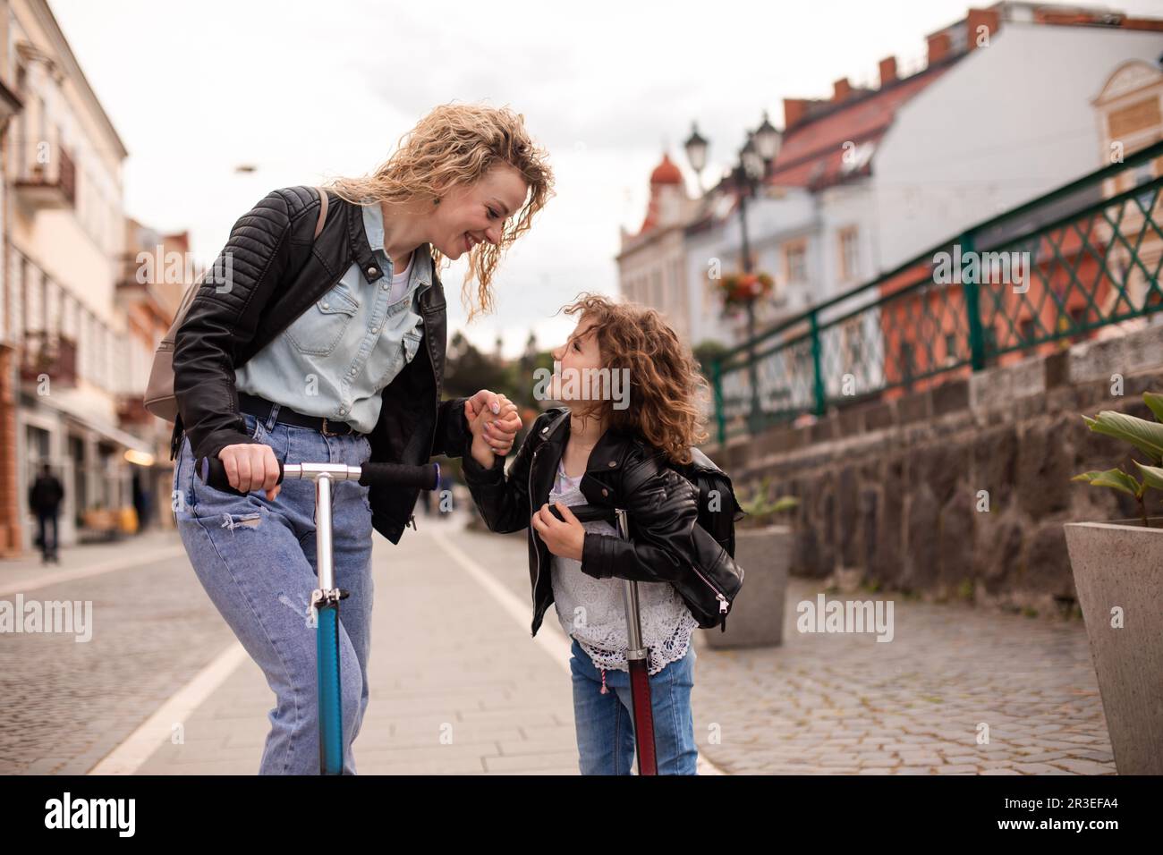 Mère et fille identiques avec des scooters dans la ville Banque D'Images