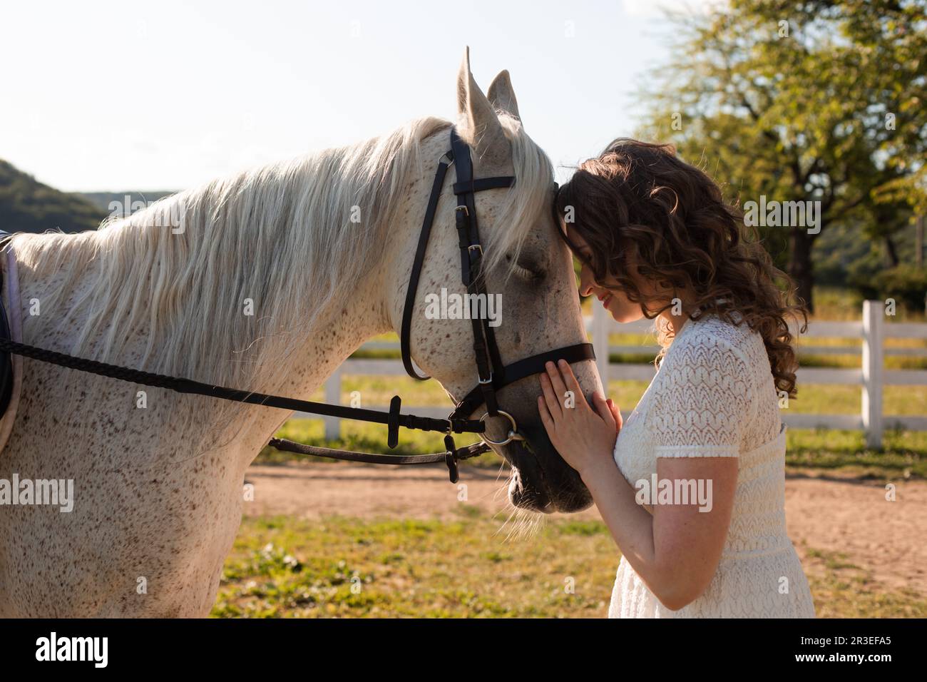 La femme avec les cheveux bouclés se caucus à son cheval Banque D'Images