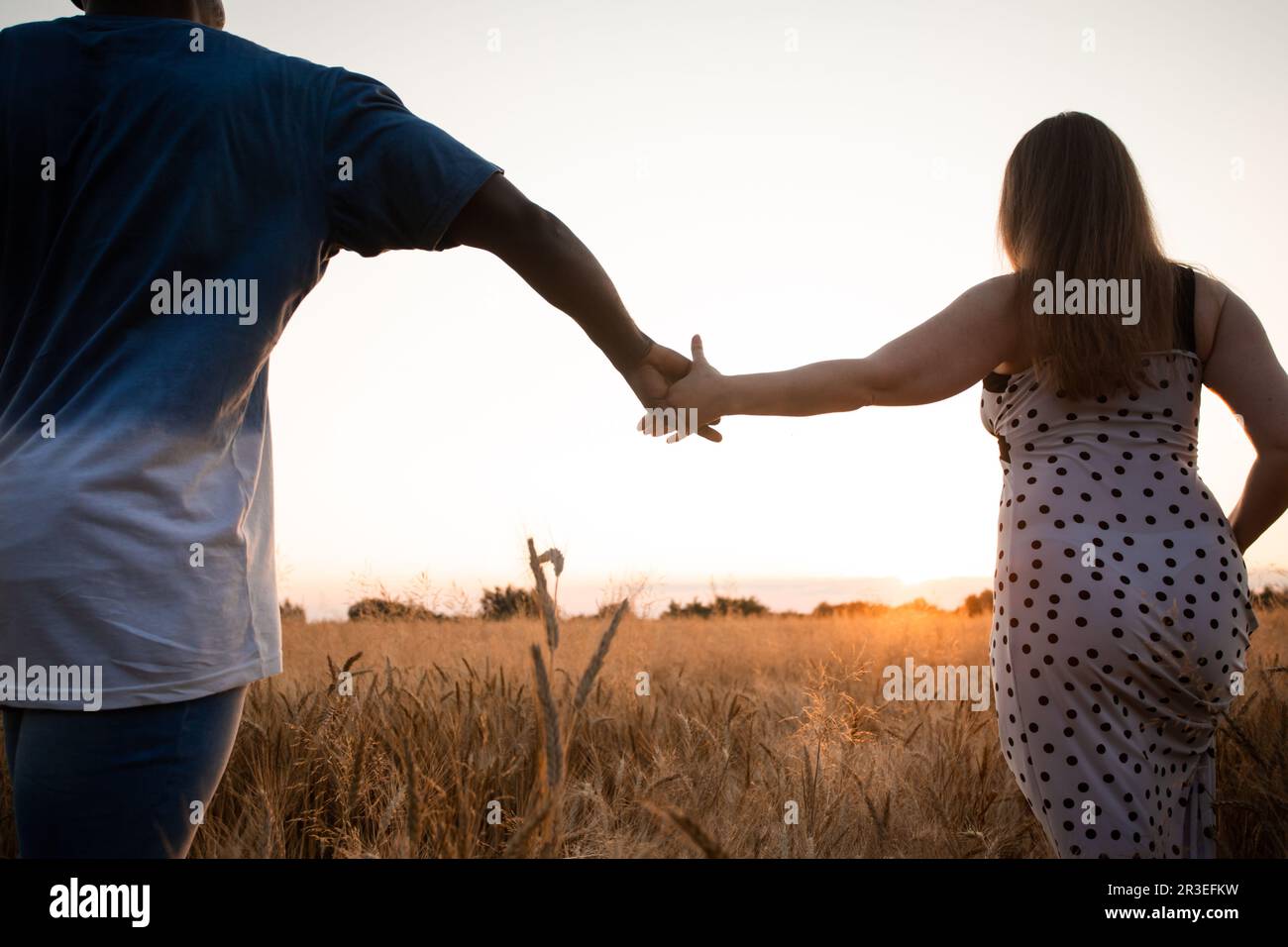 Couple tenant les mains en marchant dans le champ Banque D'Images