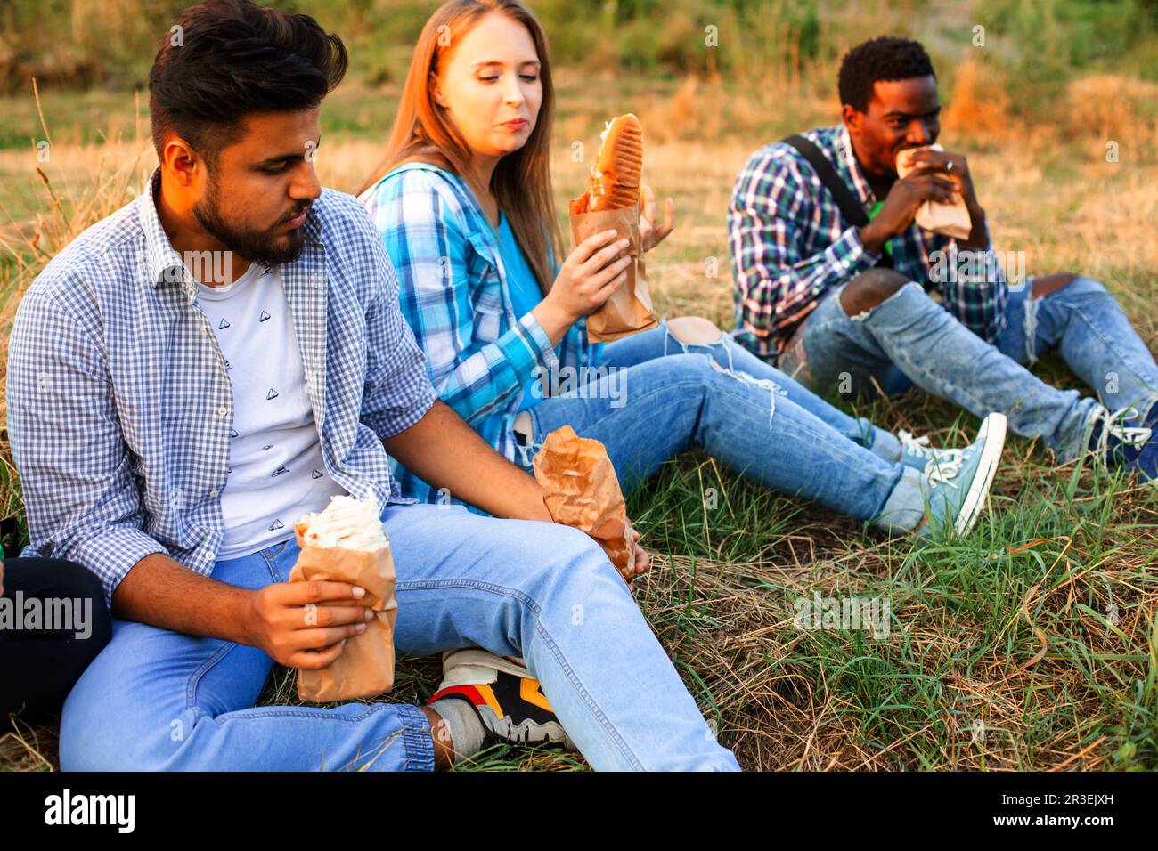 Les jeunes étudiants multiethniques qui mangent de la fastfood sur le campus Banque D'Images