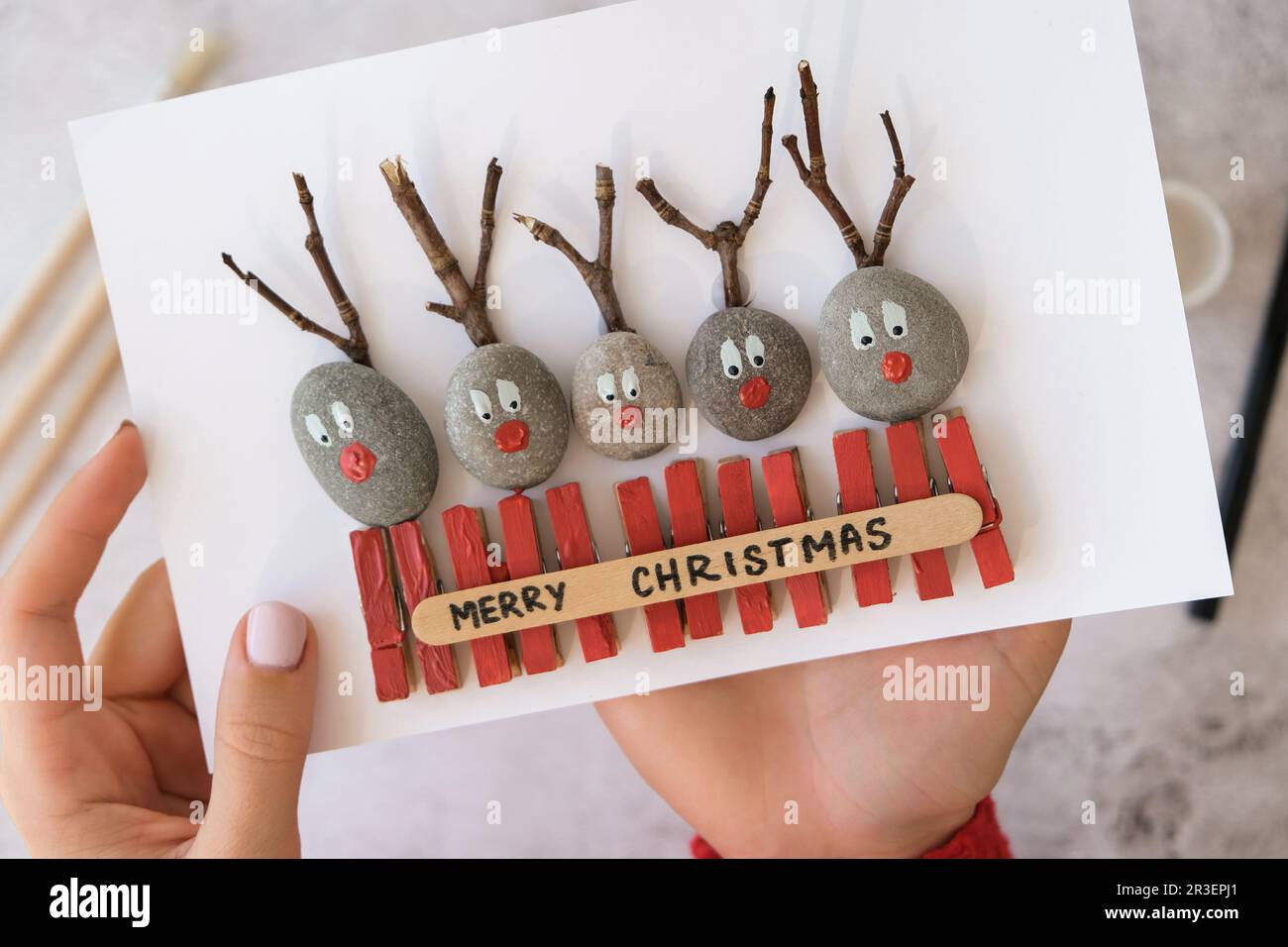 Bricolage Merry Christmas cerf sur carte de voeux carte postale faite de galets, de pierres de mer, de cloespins et de branches sur fond blanc. N/a Banque D'Images