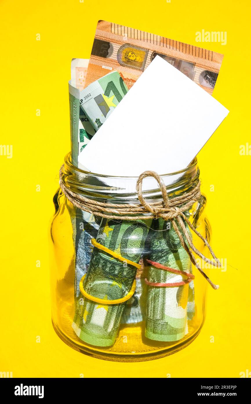 Pots en verre remplis de billets d'euros, économies à l'intérieur de pot en verre, argent isolé sur fond jaune, espace de copie pour le texte. Papier non Banque D'Images