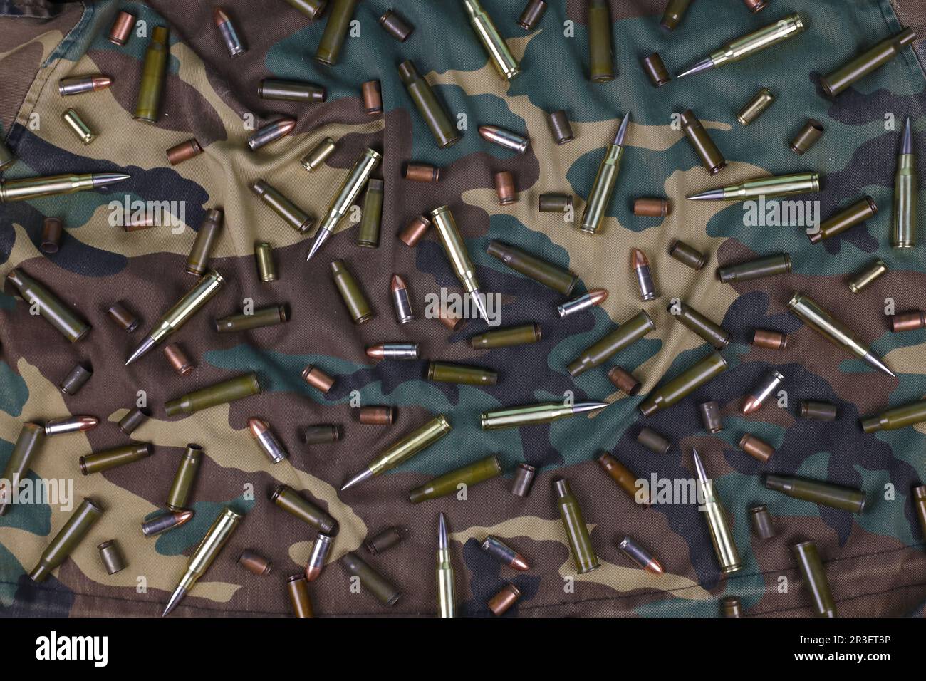 De nombreuses balles et cartouches de fusil sur fond de camouflage foncé. Concept d'action de guerre ou de chasse Banque D'Images