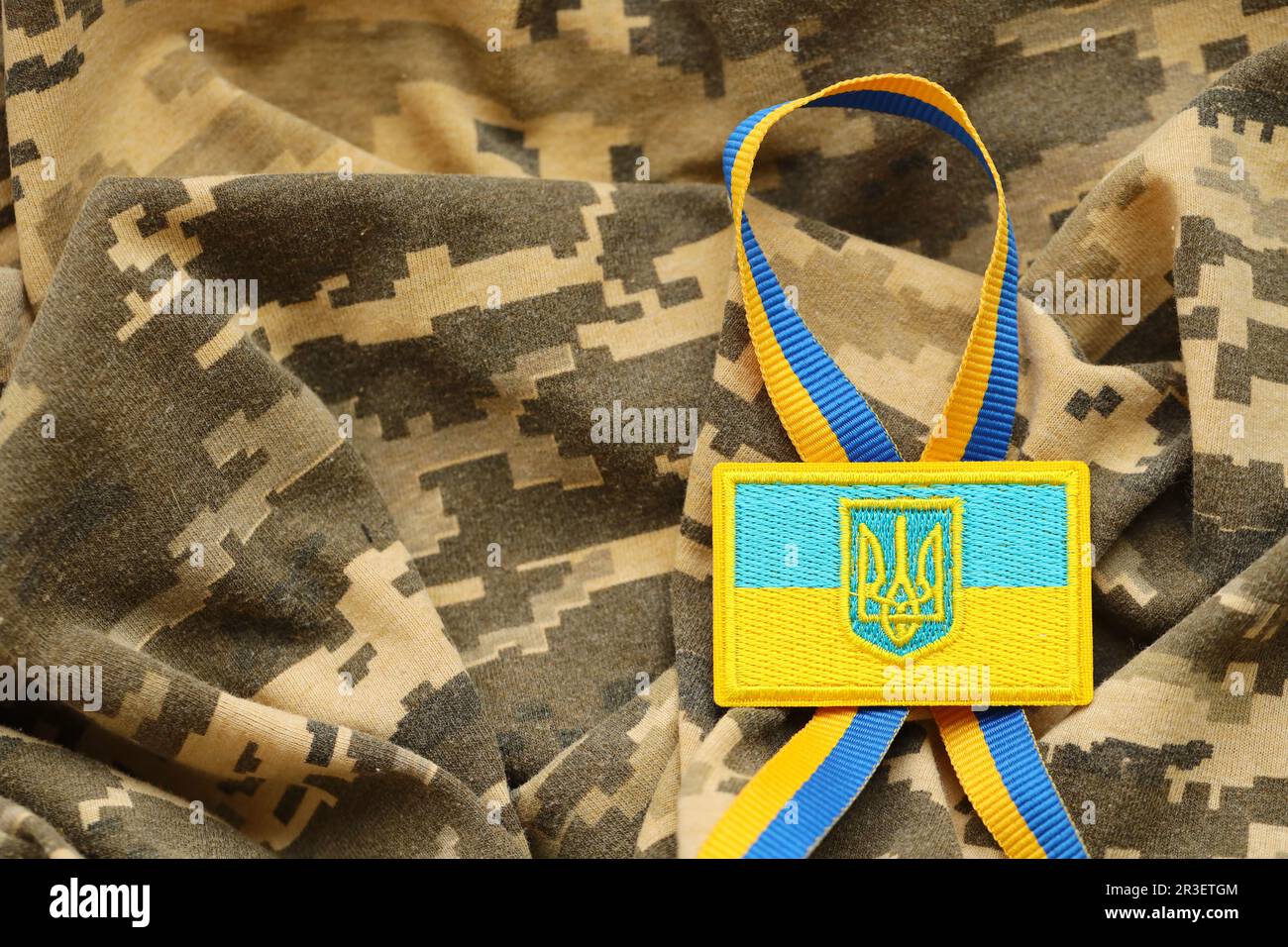 Tissu de camouflage militaire numérique Pixeled avec drapeau ukrainien et blason sur chevron en bleu et jaune. Attributs de l'uniforme de soldat ukrainien Banque D'Images