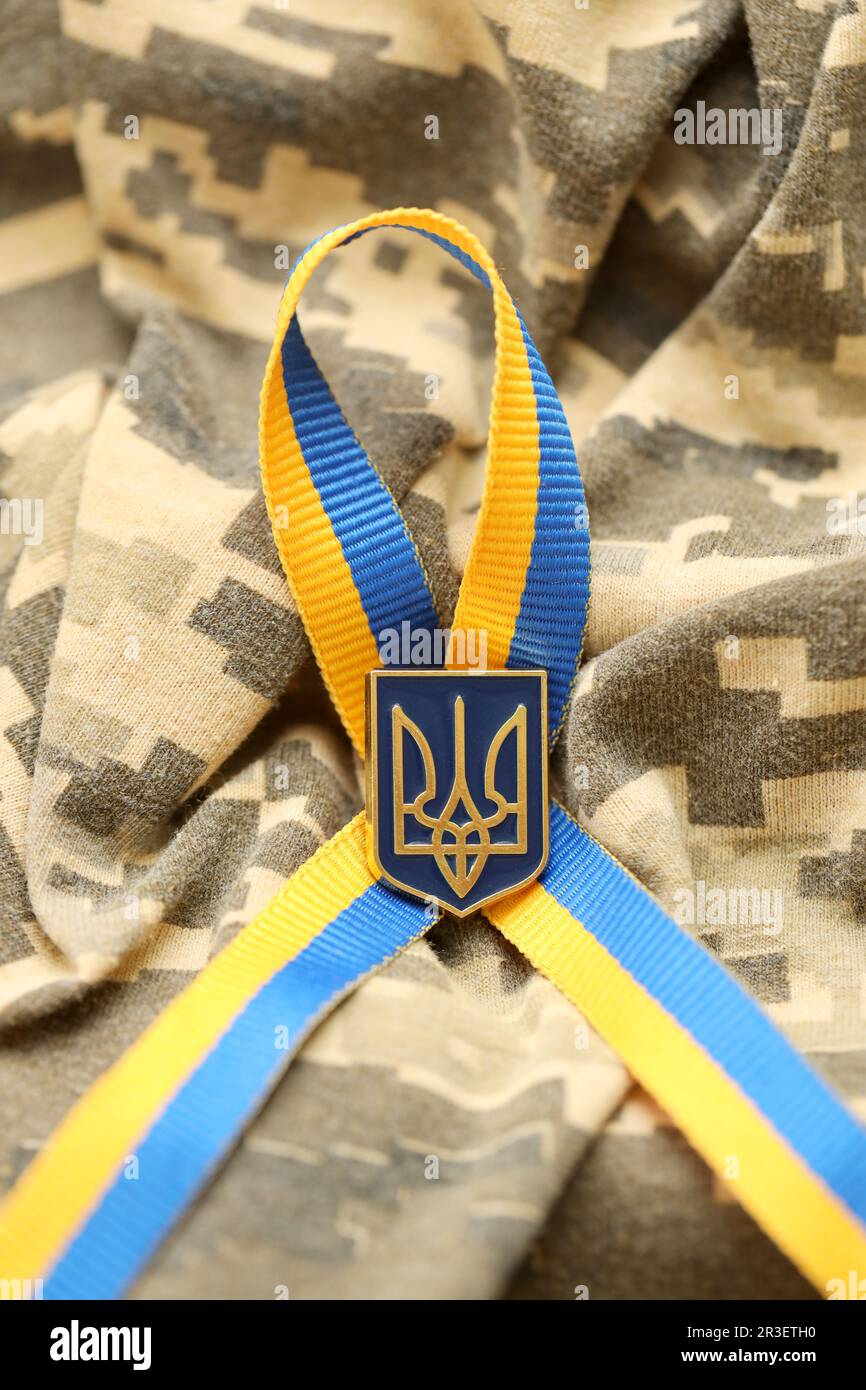 Tissu de camouflage militaire numérique Pixeled avec drapeau ukrainien et blason sur des bandes ruban bleu et jaune. Attributs de l'uniforme de soldat ukrainien Banque D'Images