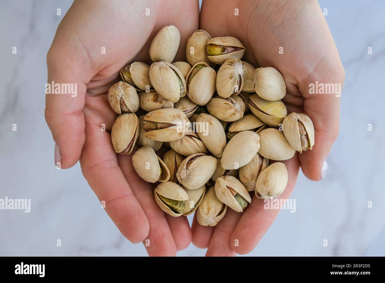 Femme mains tenant le pistache dans des noix de carapace. Aliments sains et en-cas. Pistaches super pour une alimentation saine et diététique. Concept Banque D'Images