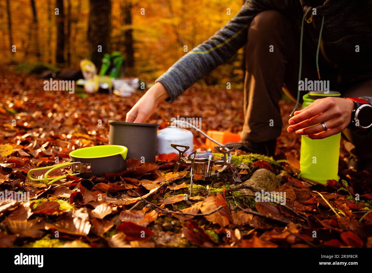 Femme utilise un chauffe-gaz portable et une poêle pour cuisiner à l'extérieur Banque D'Images