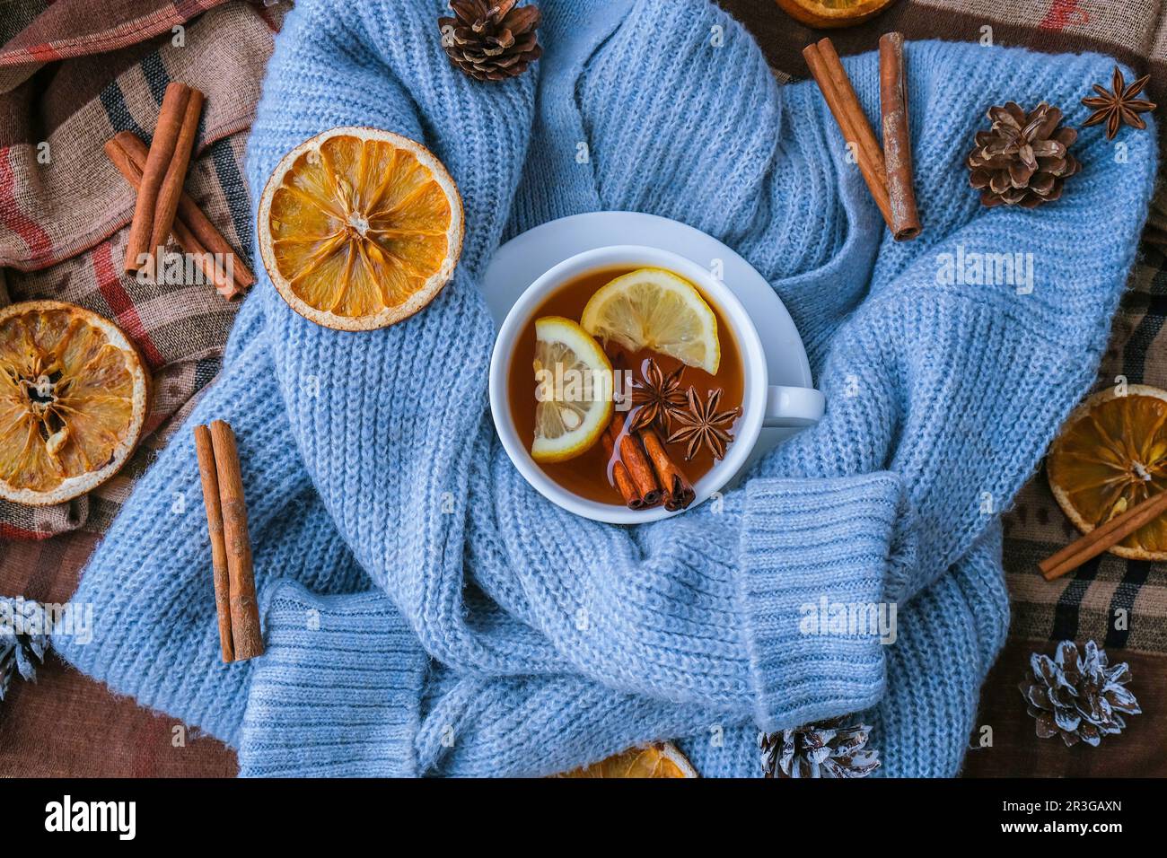 Chandail bleu et tasse de thé chaud avec bâtonnets de cannelle au citron et étoile anis. Séchez les tranches d'orange-agrumes et les cônes. Chaud hiver coc Banque D'Images