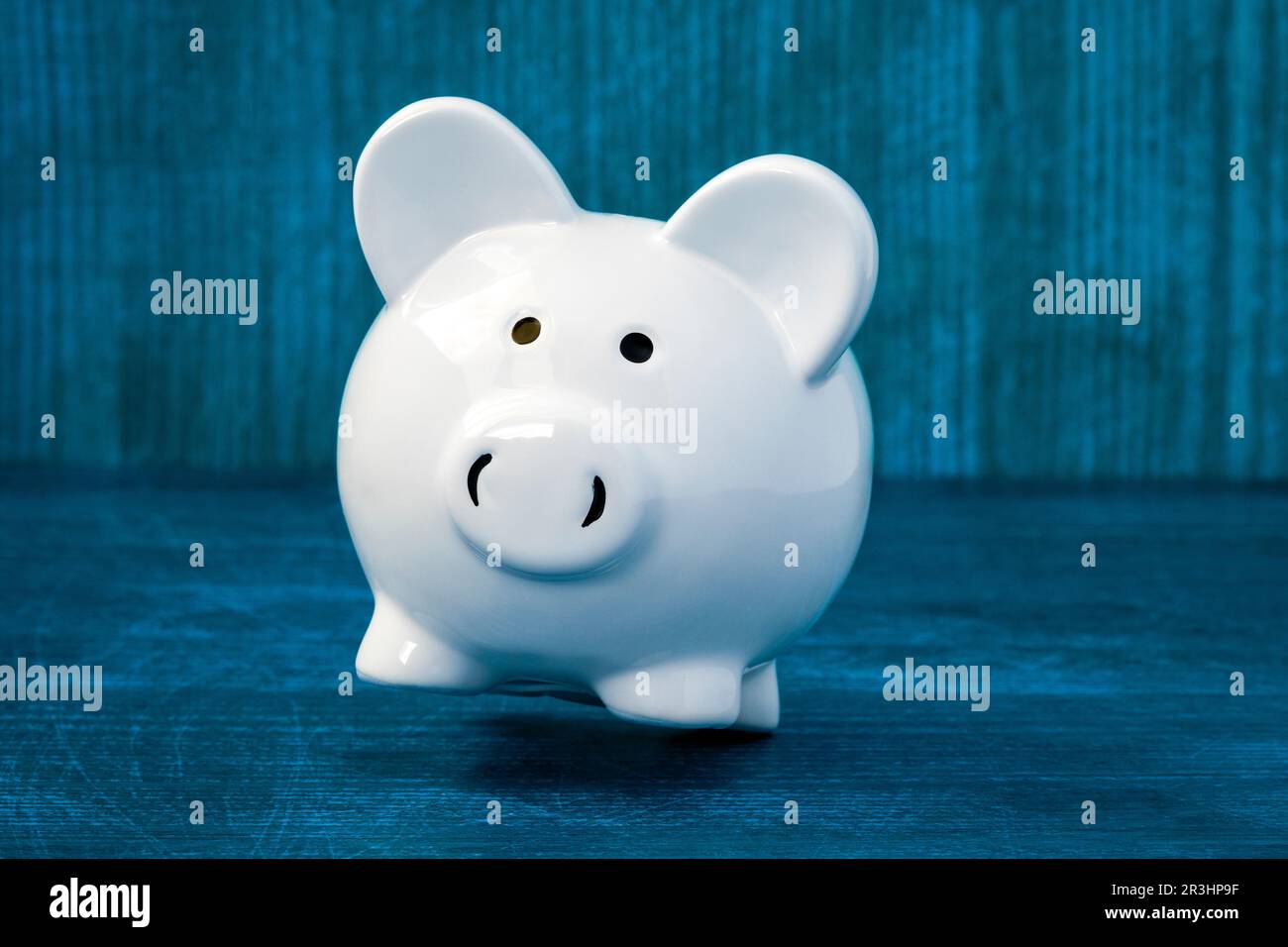 Tirelire en céramique blanche tombant sur un fond en bois bleu Banque D'Images