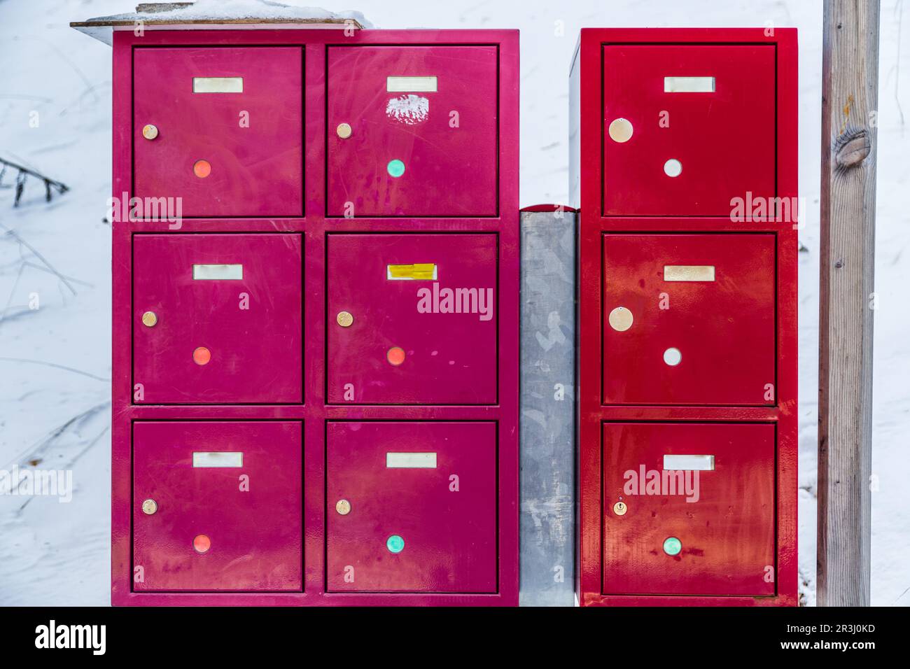 Boîtes aux lettres métalliques rouge et fuchsia dans la neige Banque D'Images