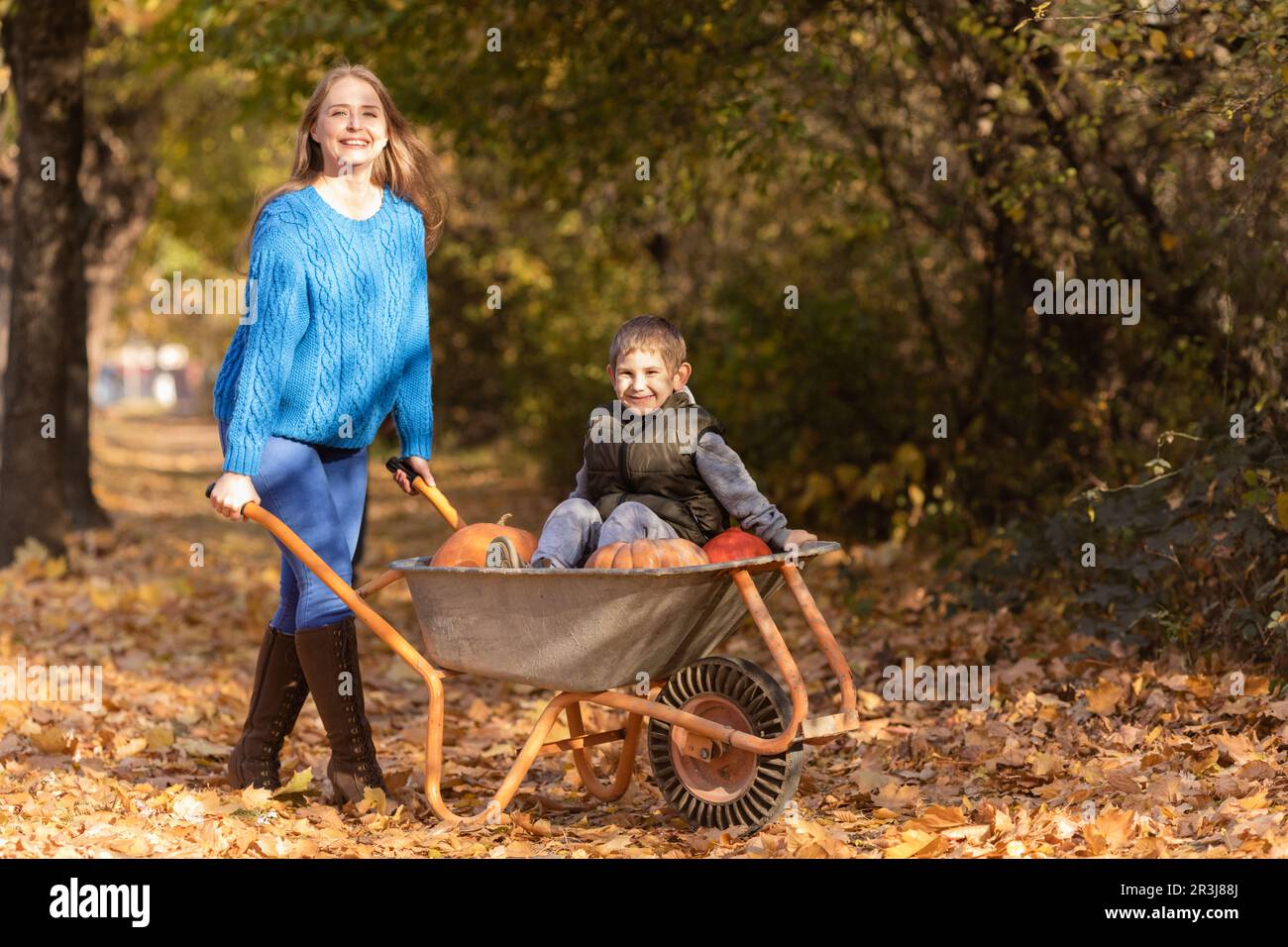 Mère amusez-vous avec les enfants, utilisez la brouette du jardin Banque D'Images