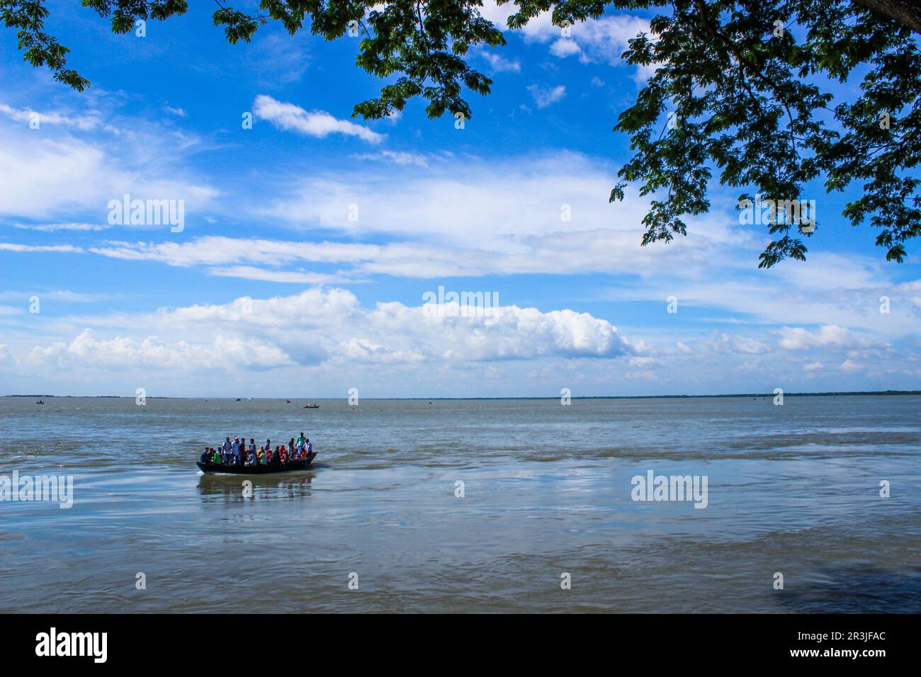 Bateau bondé sur la rivière Meghna avec une énorme vague. Ciel bleu et blanc en arrière-plan. Banque D'Images