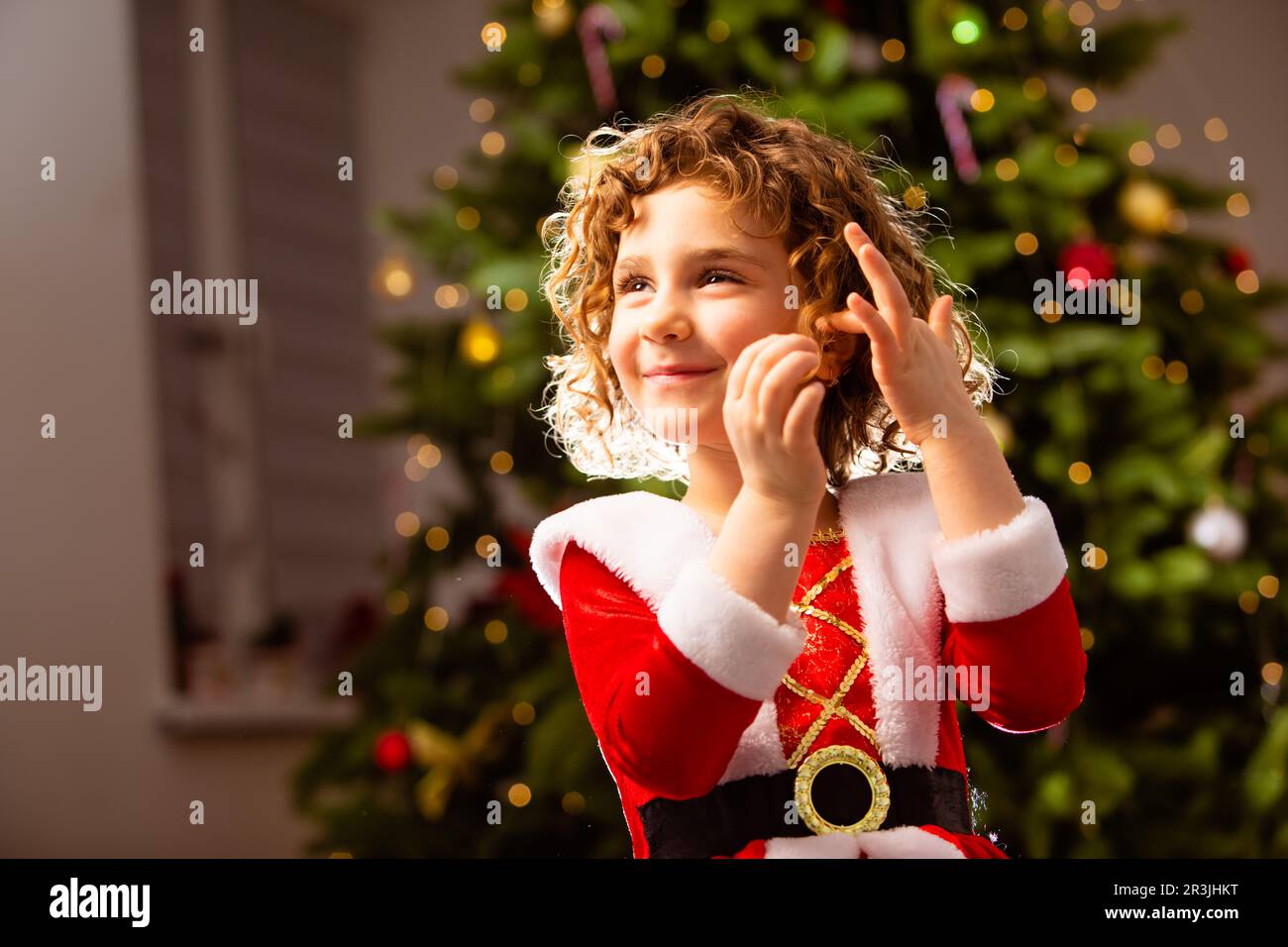 Adorable fille en robe de Noël près de l'arbre de noël classique décoré Banque D'Images